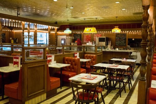 Cozy diner interior with red booths, marble tables, and vintage lighting, featuring a warm, inviting atmosphere.