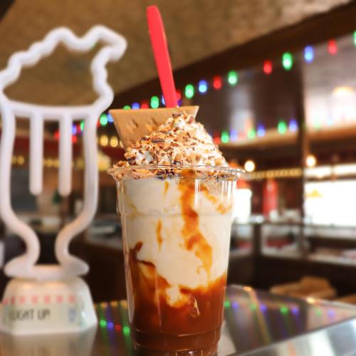 A delicious dessert in a cup with whipped cream, caramel drizzle, and a cookie, set against a colorful background.