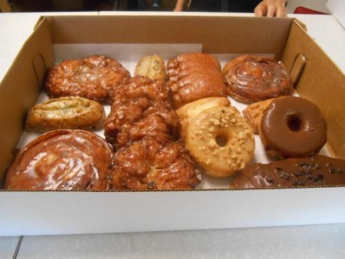 A box filled with various donuts and pastries, including glazed, chocolate, and cinnamon varieties.