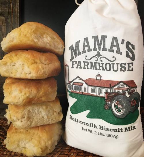 A stack of golden buttermilk biscuits next to a bag of Mama's Farmhouse Buttermilk Biscuit Mix.