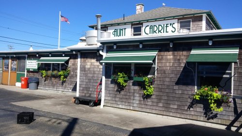 Exterior of Aunt Carrie's restaurant with green awnings, flower boxes, and an American flag flying above.