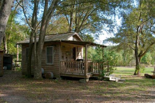 A small wooden cabin surrounded by trees, with a porch and steps leading up to the entrance.
