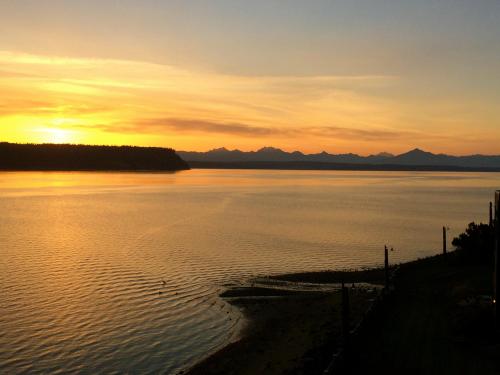 A serene sunset over a calm body of water, with mountains silhouetted in the background and gentle ripples in the foreground.