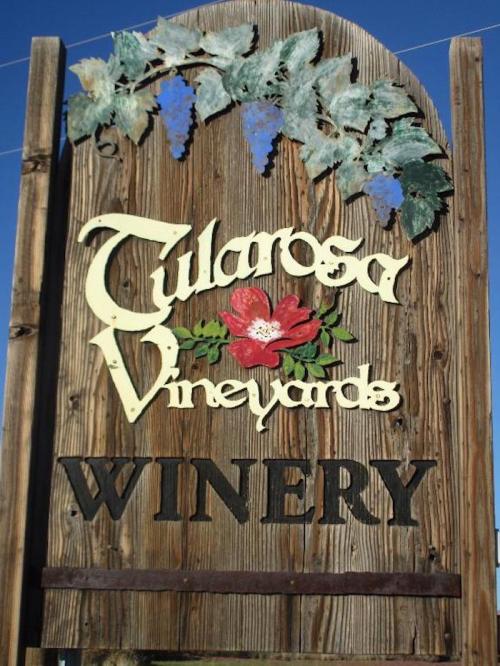 Sign for Tularosa Vineyards Winery featuring grapes and a flower design on a wooden background.
