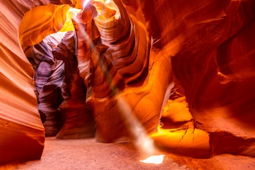 A stunning view of Antelope Canyon, showcasing vibrant orange and purple rock formations with light beams illuminating the scene.