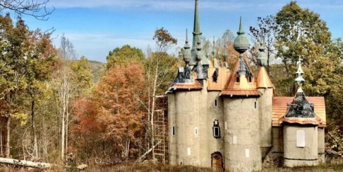 A whimsical castle with spires, surrounded by colorful autumn trees in a serene forest setting.