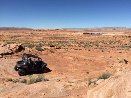 A rugged off-road vehicle parked on a rocky desert landscape under a clear blue sky.