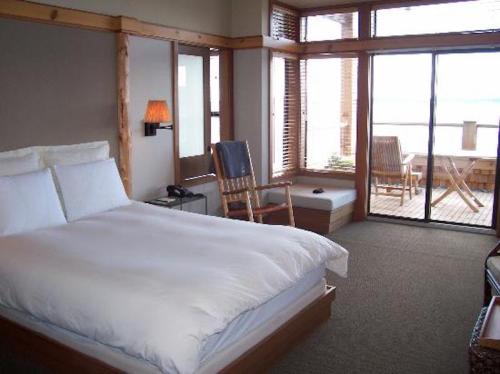 A cozy hotel room featuring a bed, wooden accents, and a balcony with outdoor seating and a view.