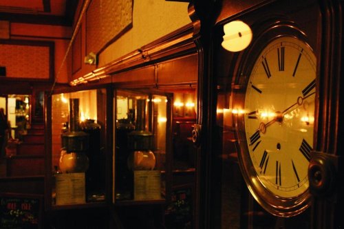 A vintage clock reflects in a dimly lit room with warm lighting and wooden decor.