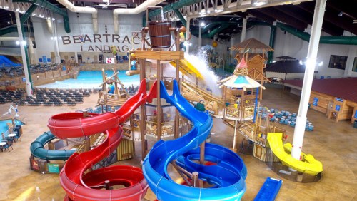 Aerial view of a vibrant indoor water park featuring colorful water slides and a large splash area.