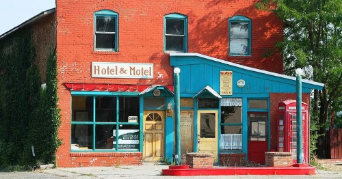 A colorful, vintage hotel and motel building with red and blue exterior, featuring large windows and a sign.