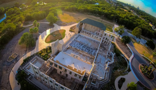 Aerial view of a partially demolished building surrounded by greenery and pathways.