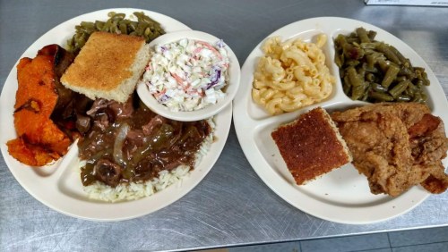 Two plates of Southern-style food featuring fried chicken, macaroni and cheese, greens, coleslaw, cornbread, and sweet potatoes.