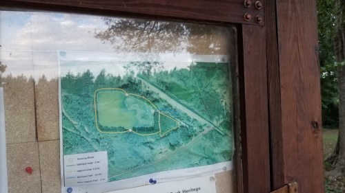 Map displayed on a bulletin board, showing a park layout with trails and designated areas outlined in yellow.