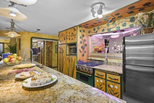 A colorful kitchen with floral decor, granite countertops, and a platter of sushi and snacks in the foreground.