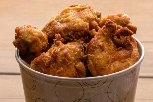 A bucket filled with crispy, golden-brown fried chicken pieces.