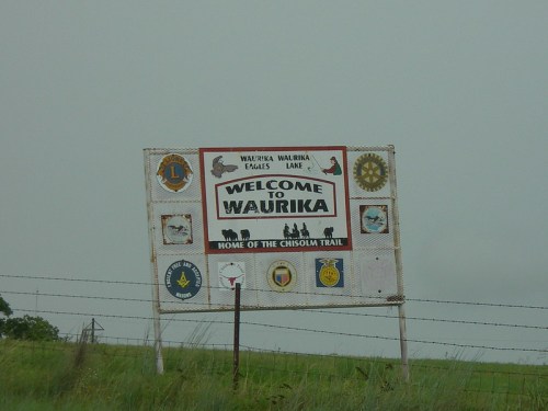 Sign welcoming visitors to Waurika, featuring local symbols and information about the Chisholm Trail.