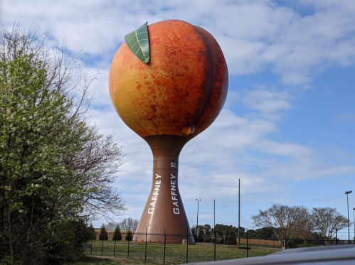 Gaffney, SC water tower shaped like a giant peach, with a green leaf on top, against a blue sky.