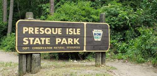 Wooden sign for Presque Isle State Park surrounded by greenery, indicating conservation and natural resources.