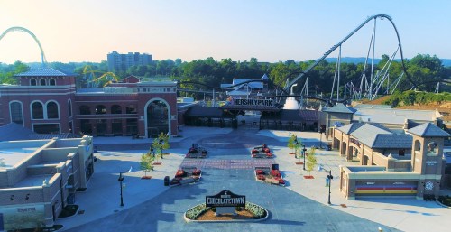Aerial view of Hersheypark entrance with rides in the background and a vibrant, sunny atmosphere.