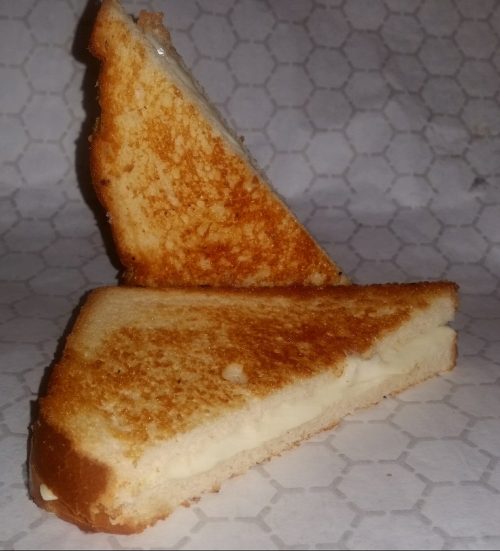 A toasted sandwich cut into two triangular pieces, showcasing a golden-brown crust and creamy filling.