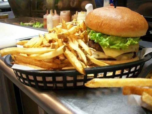 A juicy cheeseburger with lettuce and fries served in a basket on a countertop.