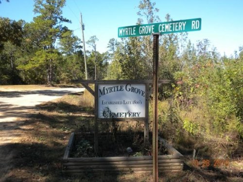 Sign for Myrtle Grove Cemetery Road, featuring a wooden sign with the cemetery's name and establishment date.