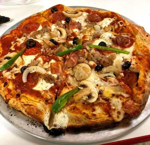 A large pizza topped with pepperoni, sausage, mushrooms, olives, green peppers, and onions on a golden crust.