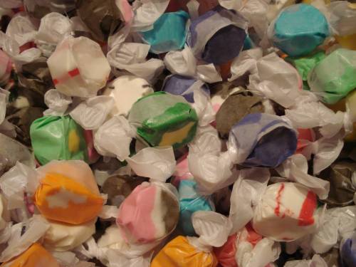 A colorful assortment of wrapped candies in various shapes and colors scattered on a surface.