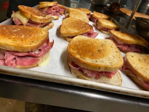 A tray of toasted sandwiches filled with layers of ham and cheese, ready to be served.