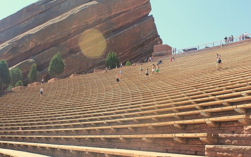 A wide view of the Red Rocks Amphitheatre, showcasing wooden seating and visitors enjoying the outdoor space.