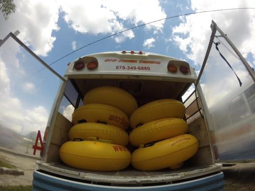 A bus trunk filled with yellow inner tubes, set against a cloudy sky.
