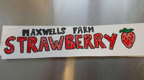 Handwritten sign reading "Maxwells Farm Strawberry" with a red strawberry illustration.