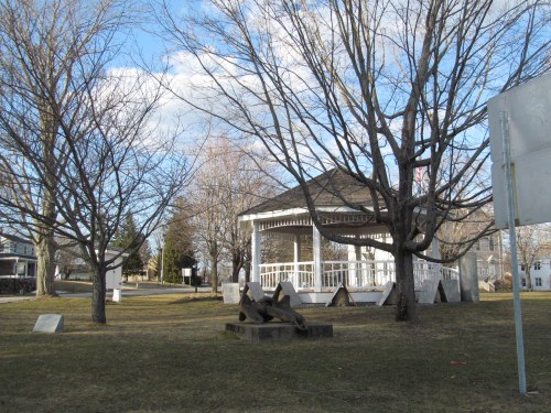 A park scene featuring a gazebo, bare trees, and grassy areas under a partly cloudy sky.