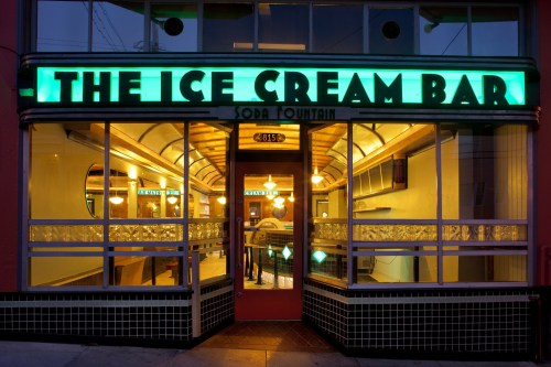A vintage ice cream bar entrance with neon signage, warm lighting, and a welcoming atmosphere.