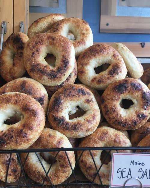 A stack of golden-brown bagels with a crispy exterior, displayed in a wire basket.