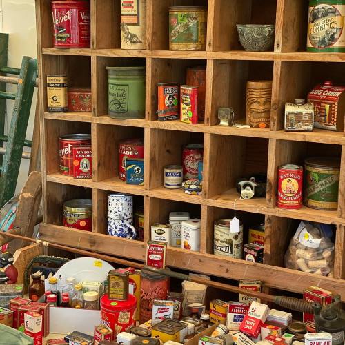 A wooden shelf filled with vintage cans and jars, showcasing various colorful labels and nostalgic packaging.