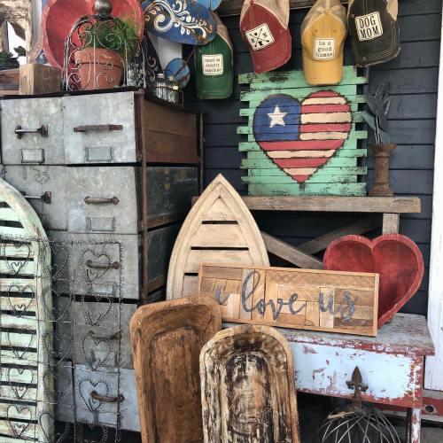 A collection of rustic decor items, including wooden hearts, a sign that says "Love Us," and colorful hats.