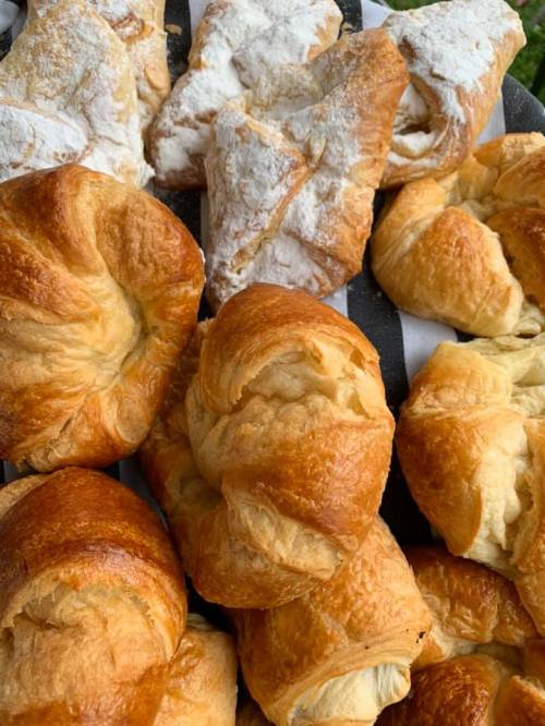 A close-up of freshly baked pastries, including croissants and puff pastries, arranged on a tray.