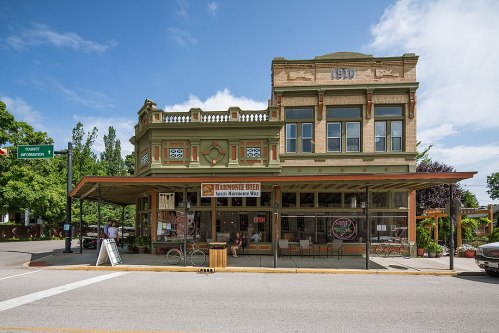 Historic building with a green facade, featuring a café and outdoor seating under a canopy on a sunny day.