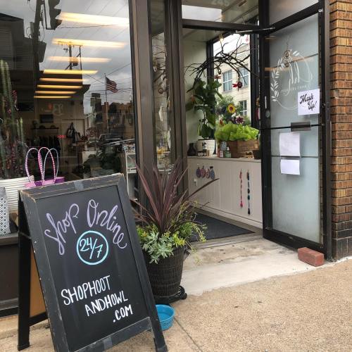 A storefront with a sign reading "Shop Online 24/7" and plants outside, inviting customers to enter.
