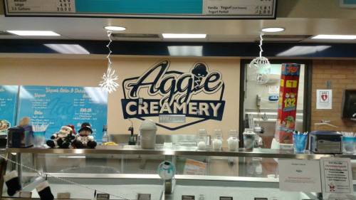 Interior of Aggie Creamery with a menu board, ice cream machines, and festive decorations.