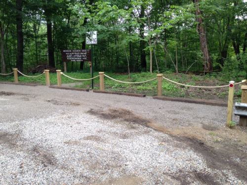 A gravel path leads to a wooded area with a sign for the Midway Arboretum Society, surrounded by trees.