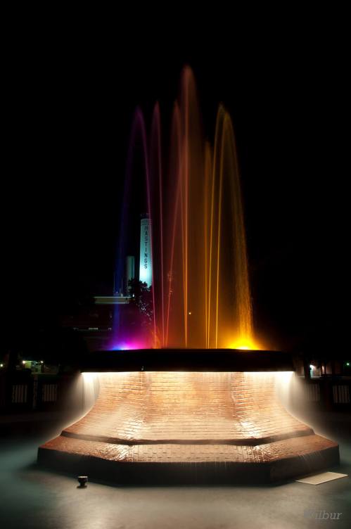 A brightly lit fountain at night, with colorful water jets and a serene atmosphere.