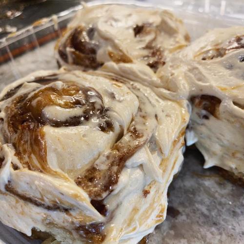 Close-up of three cinnamon rolls topped with creamy frosting, showcasing swirls of cinnamon and caramel.