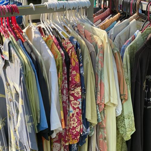 A rack of colorful shirts, including floral and patterned designs, hanging neatly on hangers.