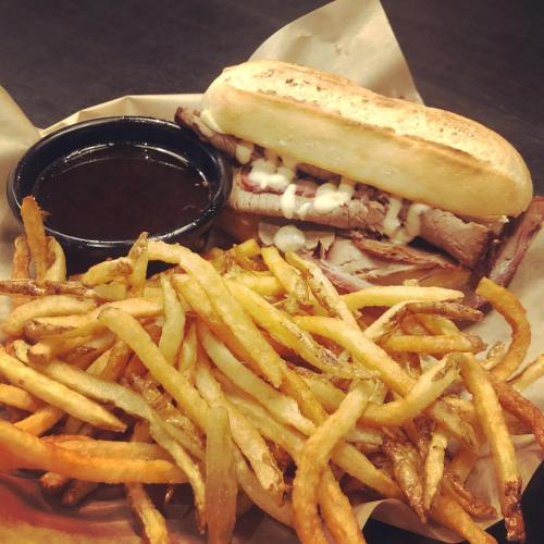 A plate featuring a beef sandwich with sauce and mayonnaise, accompanied by a side of crispy French fries.