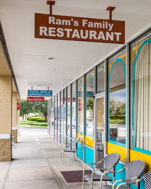 Exterior view of Ram's Family Restaurant with colorful signage and seating outside in a shopping plaza.