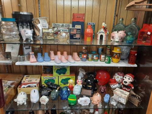 A display shelf filled with various vintage collectibles, including piggy banks, jars, and colorful figurines.