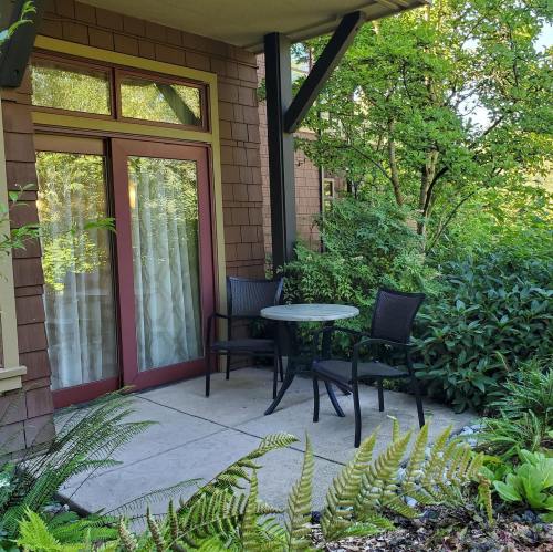 A cozy outdoor seating area with a small table and chairs surrounded by lush greenery and ferns.
